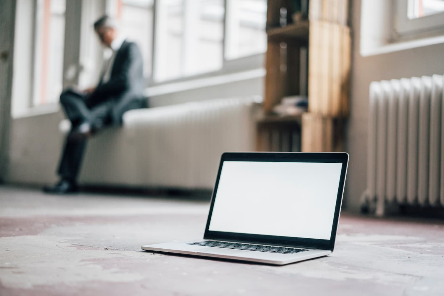 Blank laptop screen with person sitting in the background